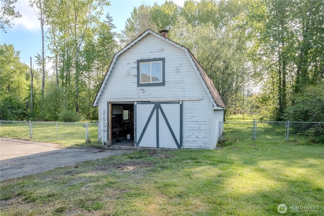 view of barn featuring a lawn, fence, and a gate