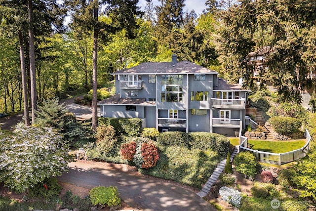 view of front of home with a balcony, a shingled roof, and a chimney