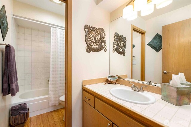 bathroom featuring toilet, wood finished floors, vanity, and shower / bath combination with curtain