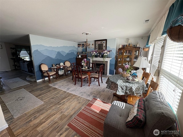 living room with a healthy amount of sunlight, a chandelier, visible vents, and wood finished floors