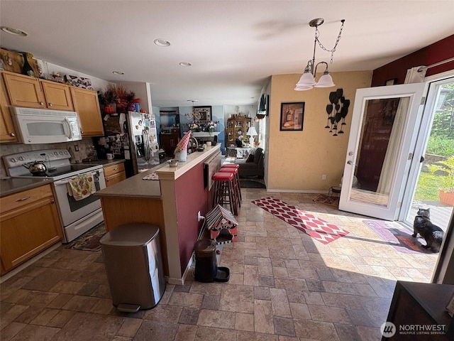 kitchen featuring white appliances, tasteful backsplash, stone tile floors, a center island, and hanging light fixtures
