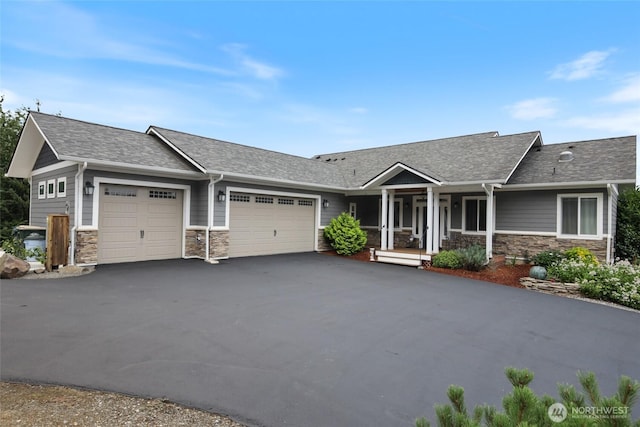 ranch-style home featuring a porch, an attached garage, aphalt driveway, stone siding, and roof with shingles