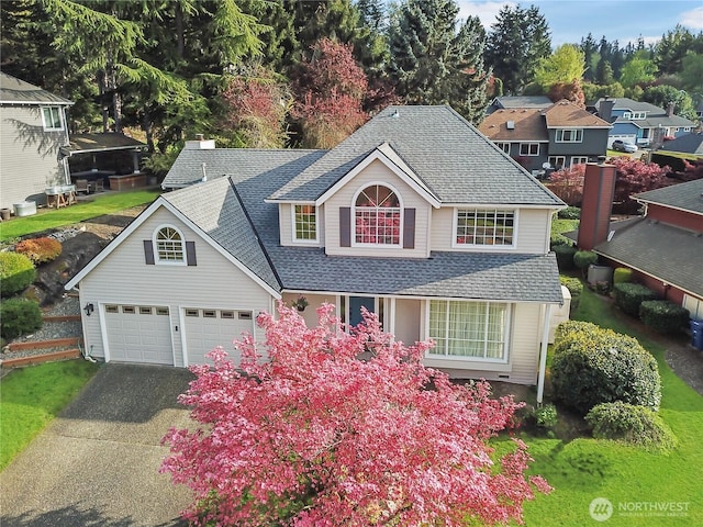 traditional home with a shingled roof and driveway