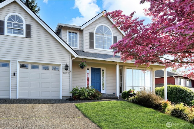 traditional-style home featuring a garage, a front lawn, and driveway