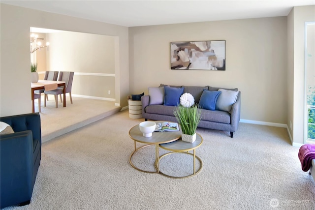 living area with an inviting chandelier, baseboards, and carpet