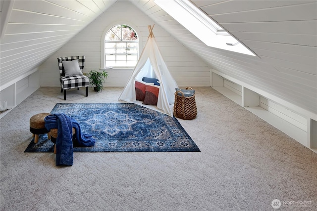 bonus room with wooden walls, carpet flooring, and lofted ceiling with skylight