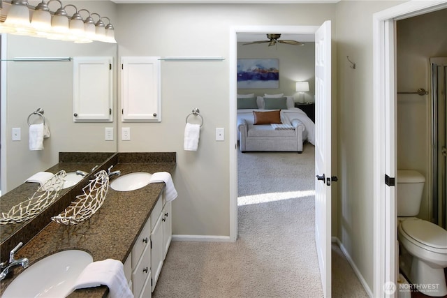 ensuite bathroom with baseboards, ceiling fan, a sink, and connected bathroom