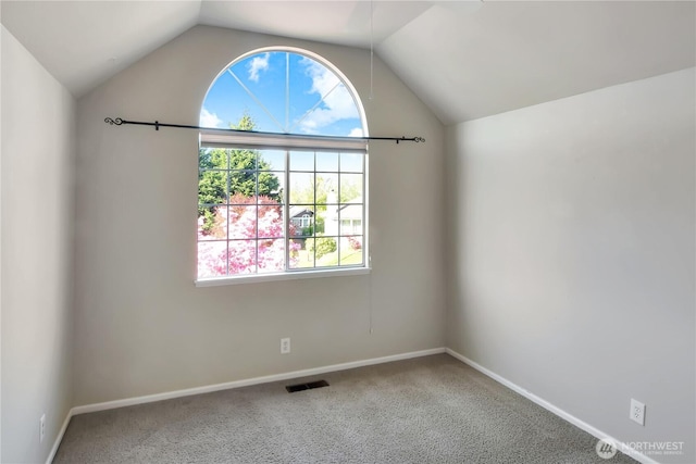 spare room with baseboards, visible vents, carpet, and lofted ceiling