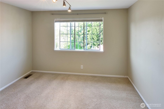 carpeted spare room featuring visible vents, baseboards, and plenty of natural light