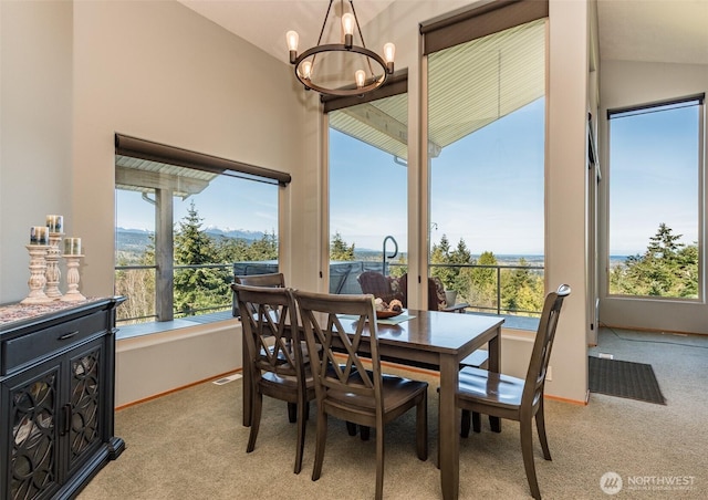 1573 Doe Run Rd, Sequim, WA 98382 - dining area featuring light carpet, vaulted ceiling, baseboards, and an inviting chandelier