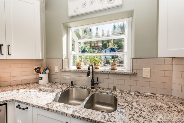 1573 Doe Run Rd, Sequim, WA 98382 - kitchen featuring white cabinets, decorative backsplash, light stone countertops, and a sink