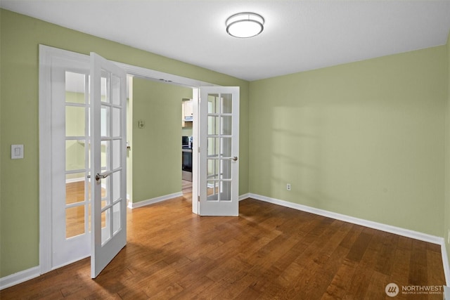 spare room with baseboards, french doors, and wood finished floors