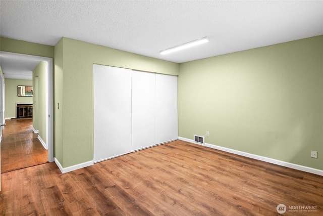 unfurnished bedroom with visible vents, baseboards, wood finished floors, and a closet