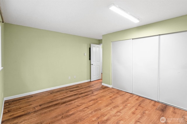unfurnished bedroom featuring a closet, baseboards, and wood finished floors