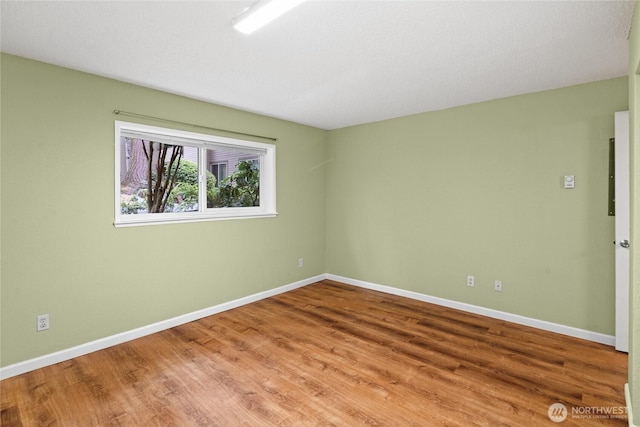 spare room with baseboards and wood finished floors