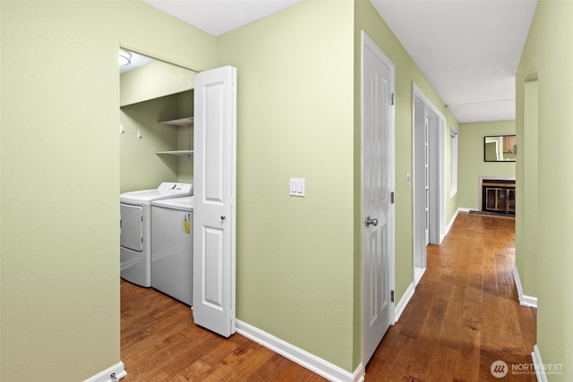 hall with baseboards, hardwood / wood-style floors, and washer and clothes dryer