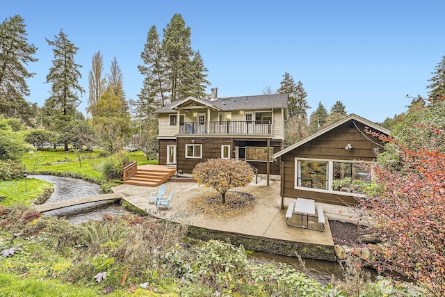 rear view of property featuring a wooden deck, a patio, and a balcony