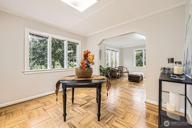 living area with arched walkways, baseboards, and ornamental molding