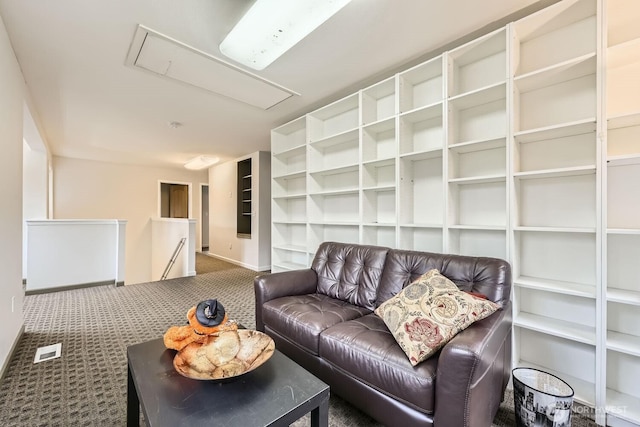carpeted living area with baseboards, visible vents, built in shelves, and attic access