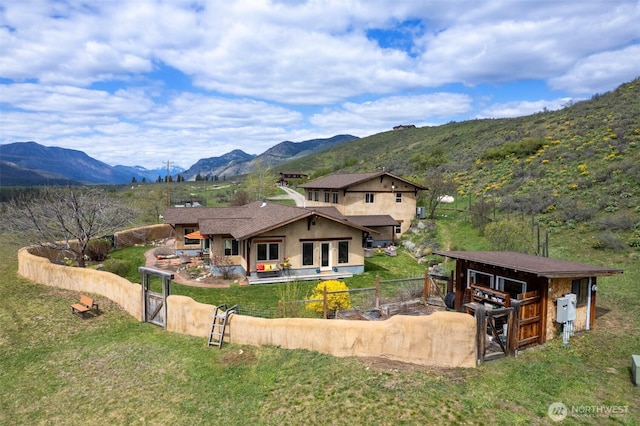 back of house with stucco siding, a gate, a mountain view, an outbuilding, and a patio area