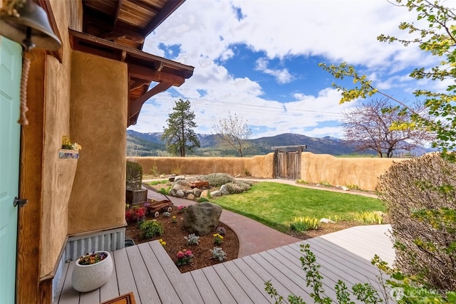 view of yard featuring a deck with mountain view and fence