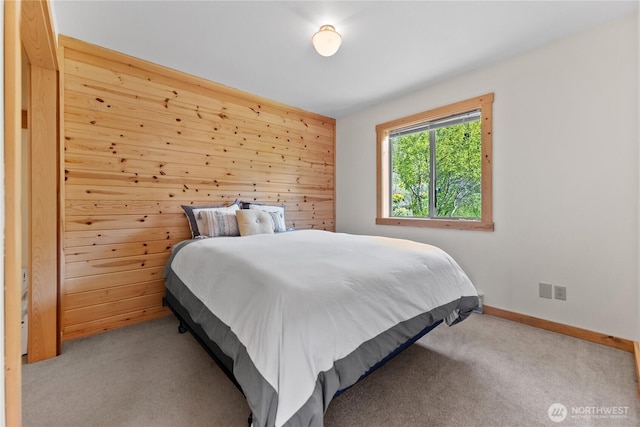 bedroom featuring carpet floors, wooden walls, and baseboards
