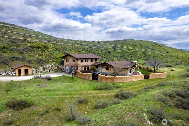 back of property with a garage, dirt driveway, a mountain view, and fence