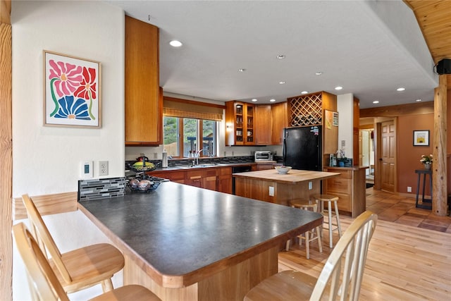 40 Rolling Rock Rd, Winthrop, WA 98862 - kitchen featuring freestanding refrigerator, butcher block countertops, a peninsula, brown cabinets, and a breakfast bar area