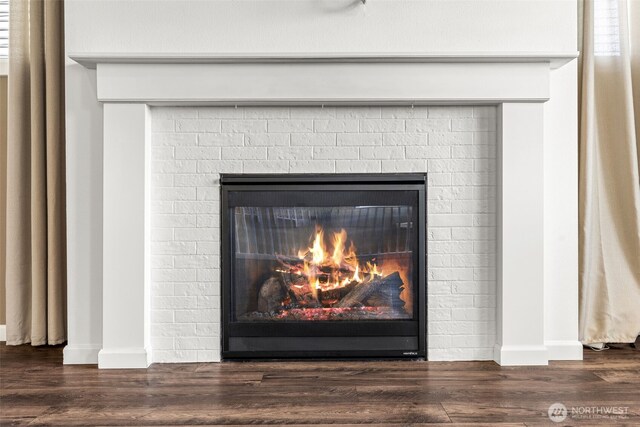 room details featuring baseboards, a glass covered fireplace, and wood finished floors