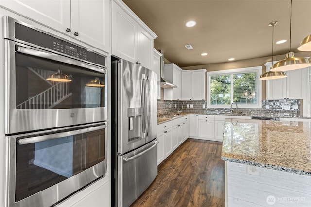 kitchen featuring dark wood-style flooring, white cabinetry, light stone counters, backsplash, and stainless steel appliances
