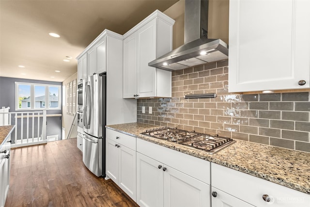 kitchen with light stone countertops, dark wood-type flooring, wall chimney exhaust hood, white cabinetry, and stainless steel appliances