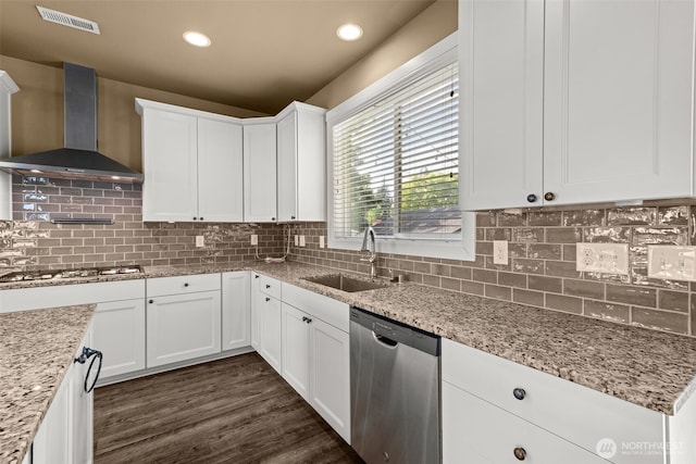 kitchen with visible vents, wall chimney exhaust hood, white cabinetry, a sink, and appliances with stainless steel finishes