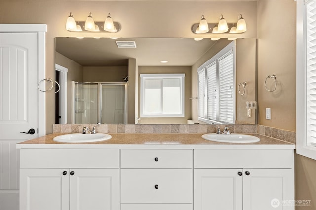 full bathroom featuring a sink, a shower stall, and double vanity