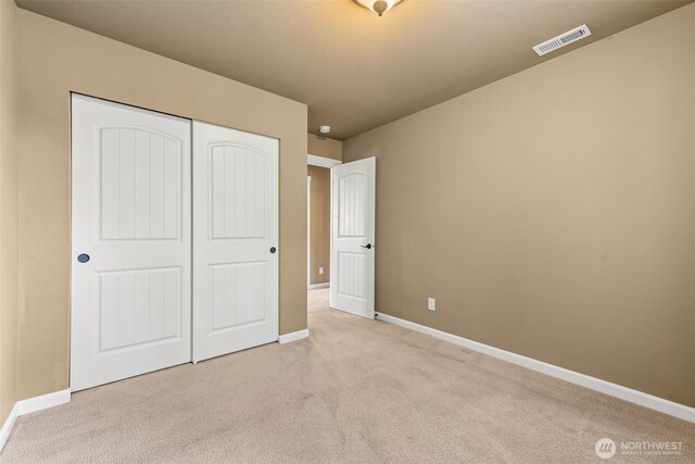 unfurnished bedroom with carpet floors, baseboards, visible vents, and a closet