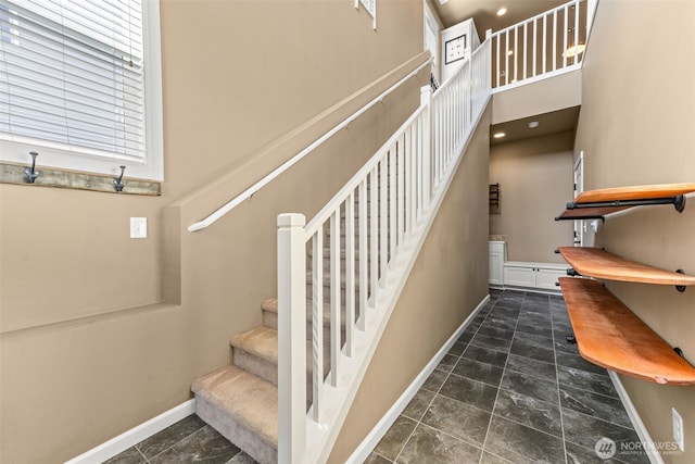 stairway featuring baseboards and a towering ceiling