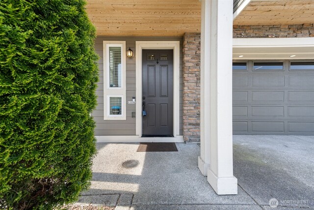 property entrance featuring a garage and stone siding