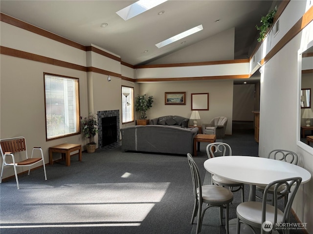 dining room featuring visible vents, a skylight, a fireplace, carpet, and recessed lighting