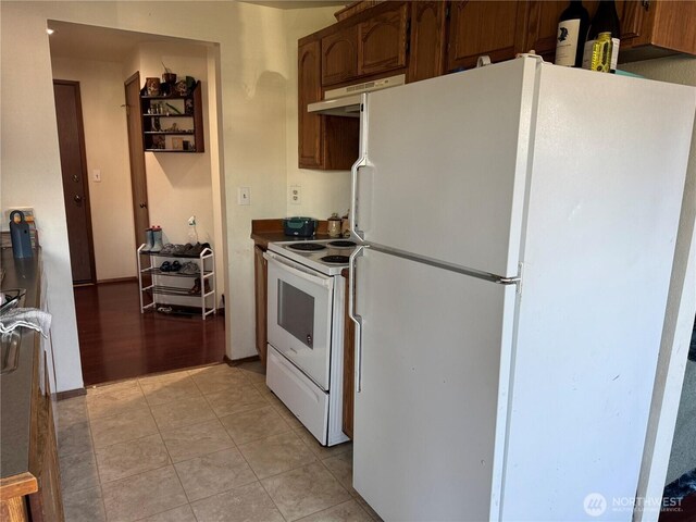 kitchen featuring white appliances, under cabinet range hood, and light tile patterned floors