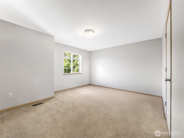 carpeted empty room featuring baseboards and visible vents
