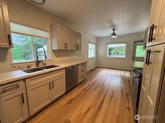 kitchen with a sink, dishwasher, electric stove, light wood-style flooring, and ceiling fan