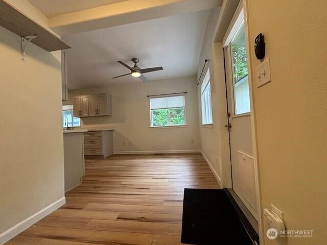 unfurnished living room with light wood finished floors, baseboards, and ceiling fan