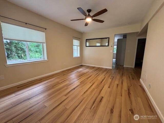 spare room featuring light wood finished floors, ceiling fan, and baseboards