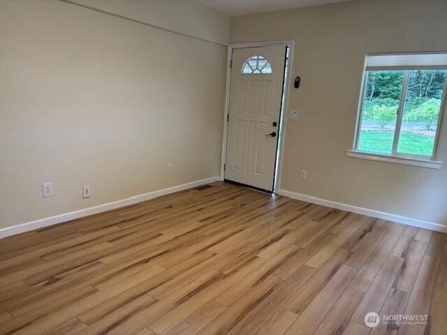 foyer entrance featuring light wood-style flooring and baseboards