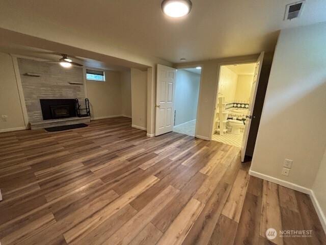 unfurnished living room featuring a fireplace, wood finished floors, and baseboards