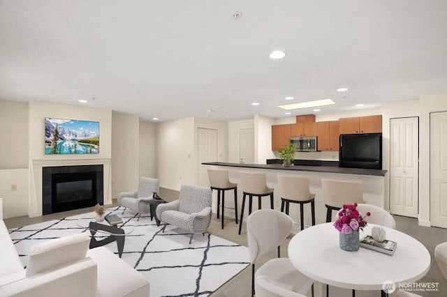 living area with recessed lighting, a tiled fireplace, and baseboards
