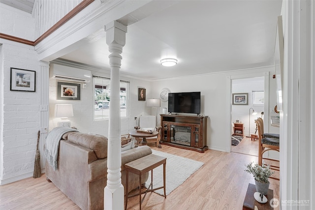 1506 163rd Pl, Long Beach, WA 98631 - living area with a wall mounted air conditioner, decorative columns, crown molding, a glass covered fireplace, and light wood-style floors