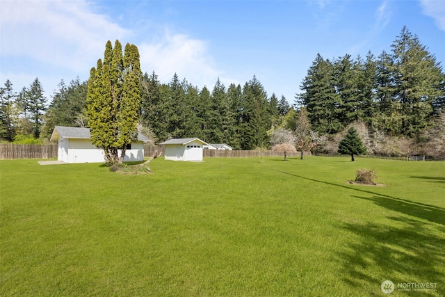 view of yard with fence, an outdoor structure, and a storage shed
