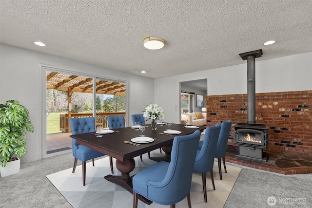 dining area with recessed lighting, a textured ceiling, light colored carpet, and a wood stove