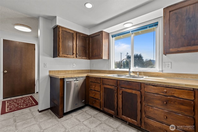 kitchen with light countertops, a sink, light floors, and dishwasher