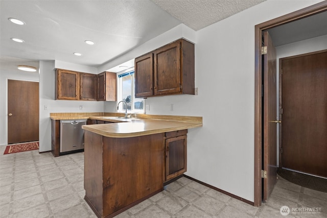 kitchen featuring light countertops, a peninsula, baseboards, light floors, and stainless steel dishwasher